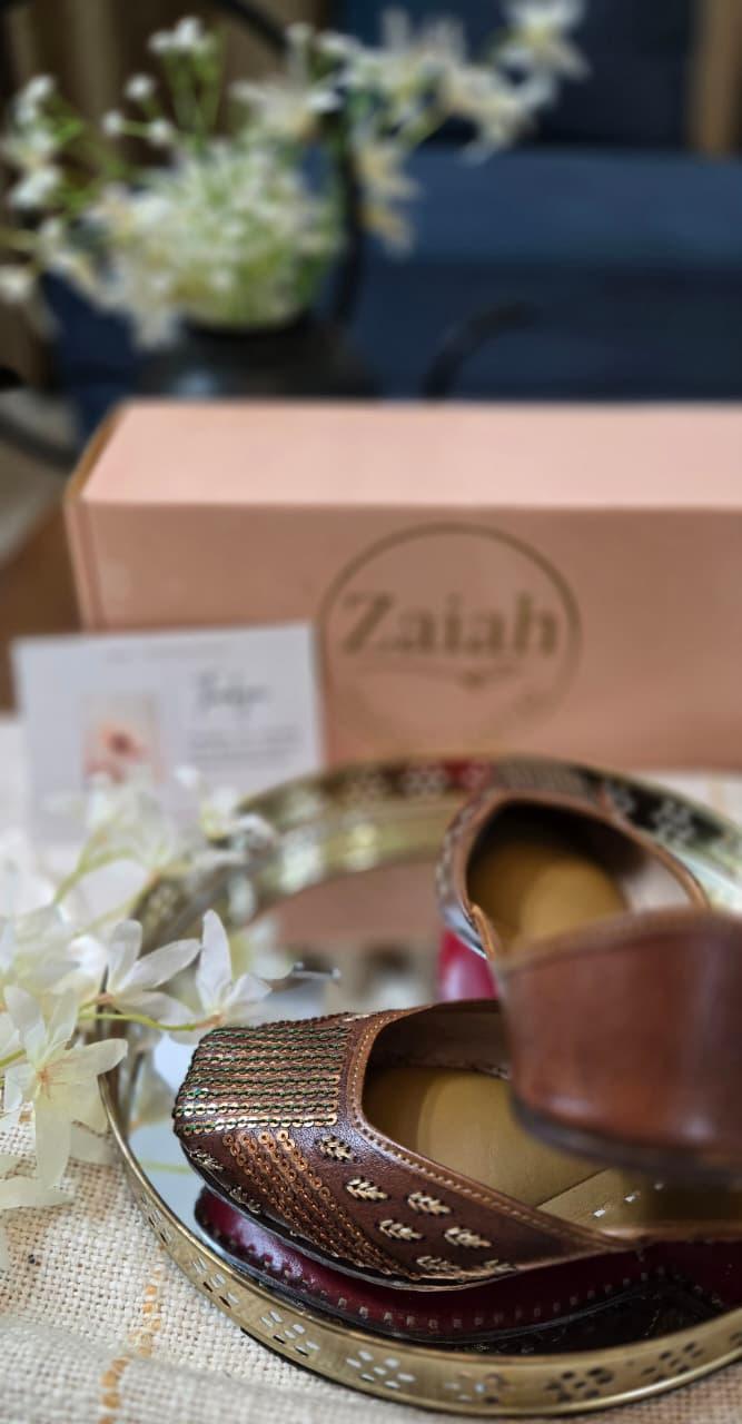 Bronzebloom jutti on a metallic tray with 'Zaiah' branding in the background