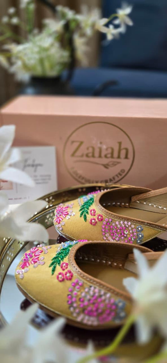 Margleam jutti with floral patterns and rhinestones on a reflective surface, with 'Zaiah' branding in the background.
